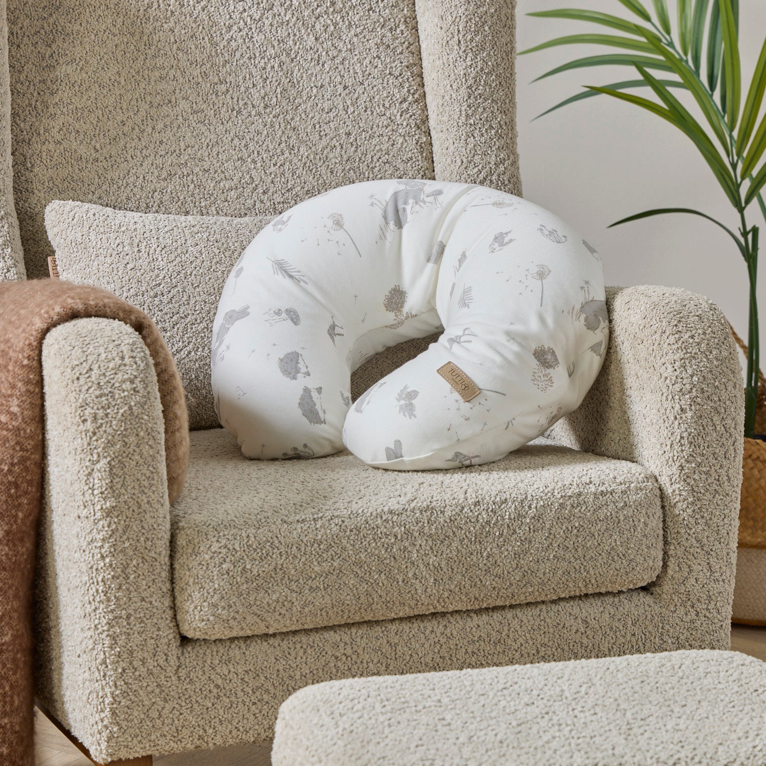 Cocoon white feeding pillow with grey woodland-inspired patterns on a beige nursing chair
