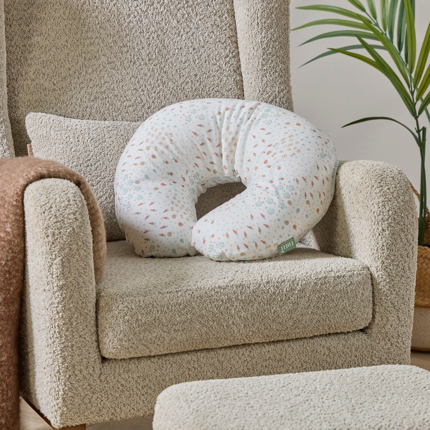 Good Life white feeding pillow with farm-inspired patterns on a beige nursing chair