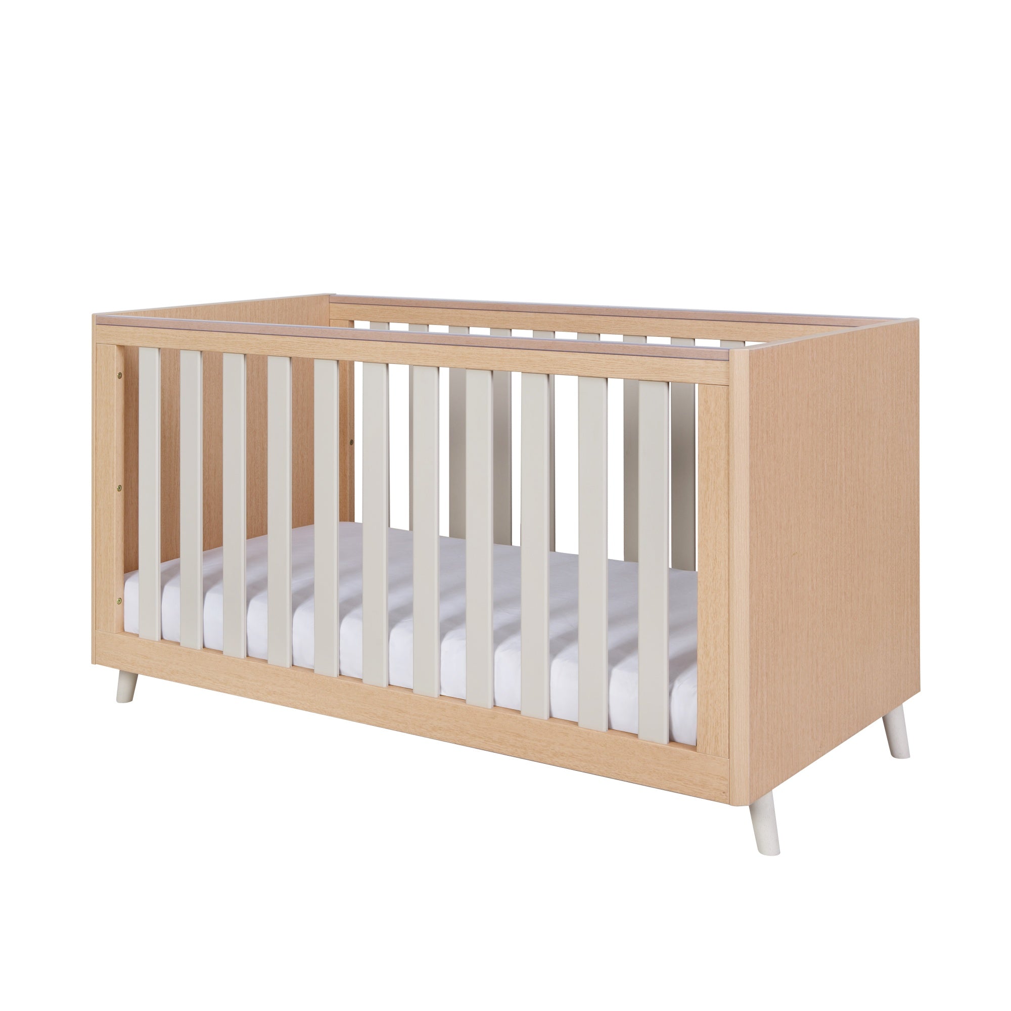 Angled view of Fika cot bed in light oak and white sand with bevelled corners, clean lines and splayed legs on a white background.