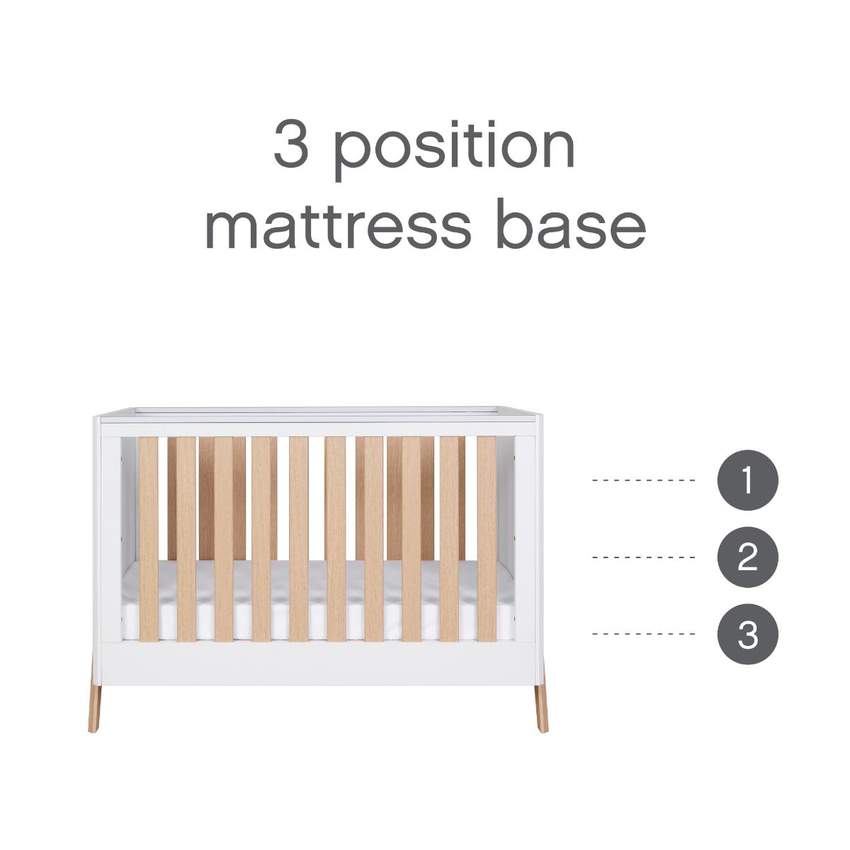 Fuori mini cot bed in white and light oak showing the three position mattress base, designed to adapt as your baby grows