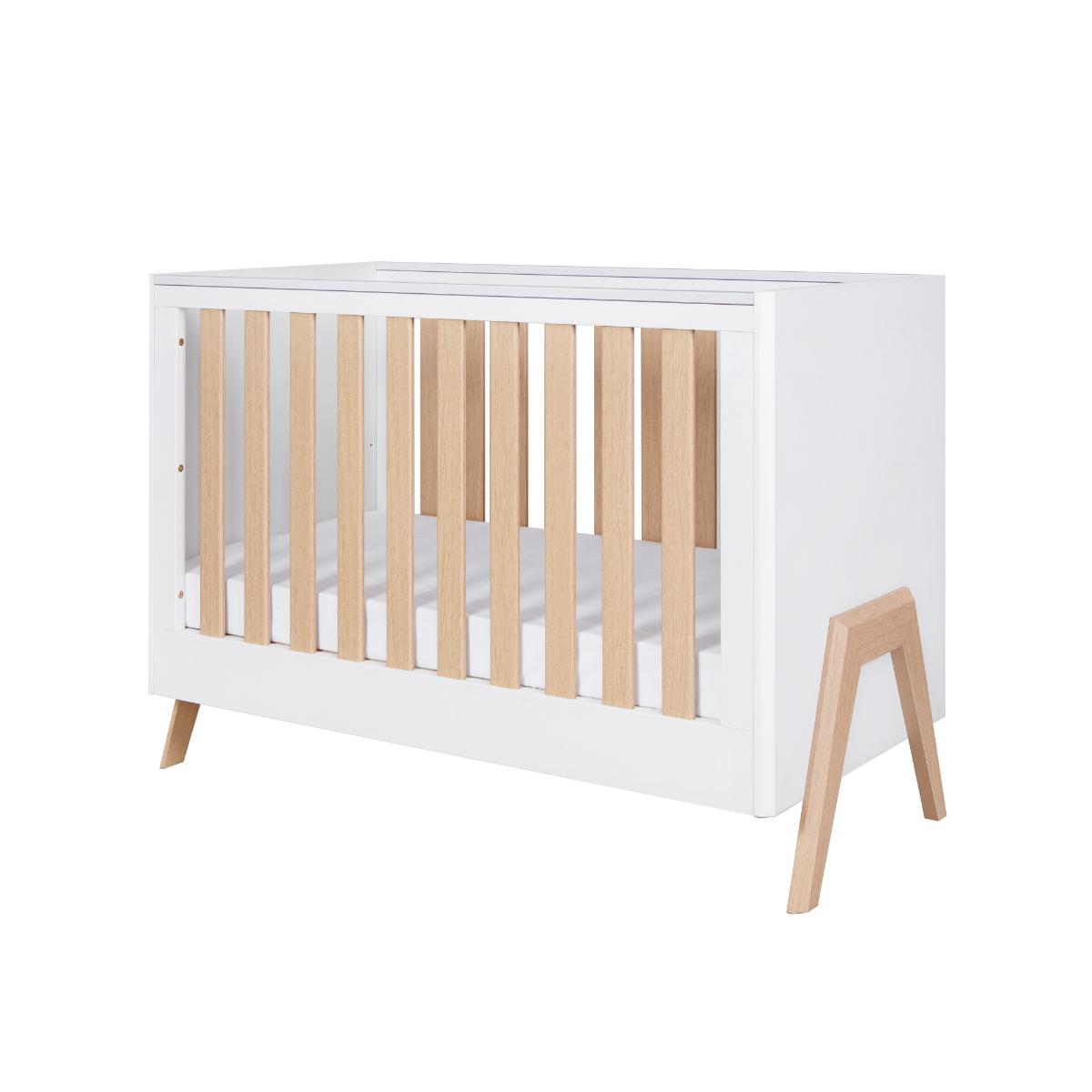 Angled cutout of the Fuori mini cot bed in white and light oak, featuring solid wood slats, compact proportions and modern detailing
