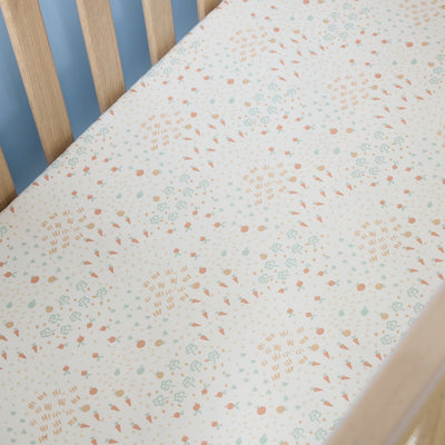 Farm-patterned cot bed sheet on a wooden cot with a light blue wall background