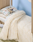 Children's bed with a patterned duvet and pillow against a light blue wall.