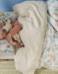 Child sleeping in a bedwith a patterned comforter and plush toy