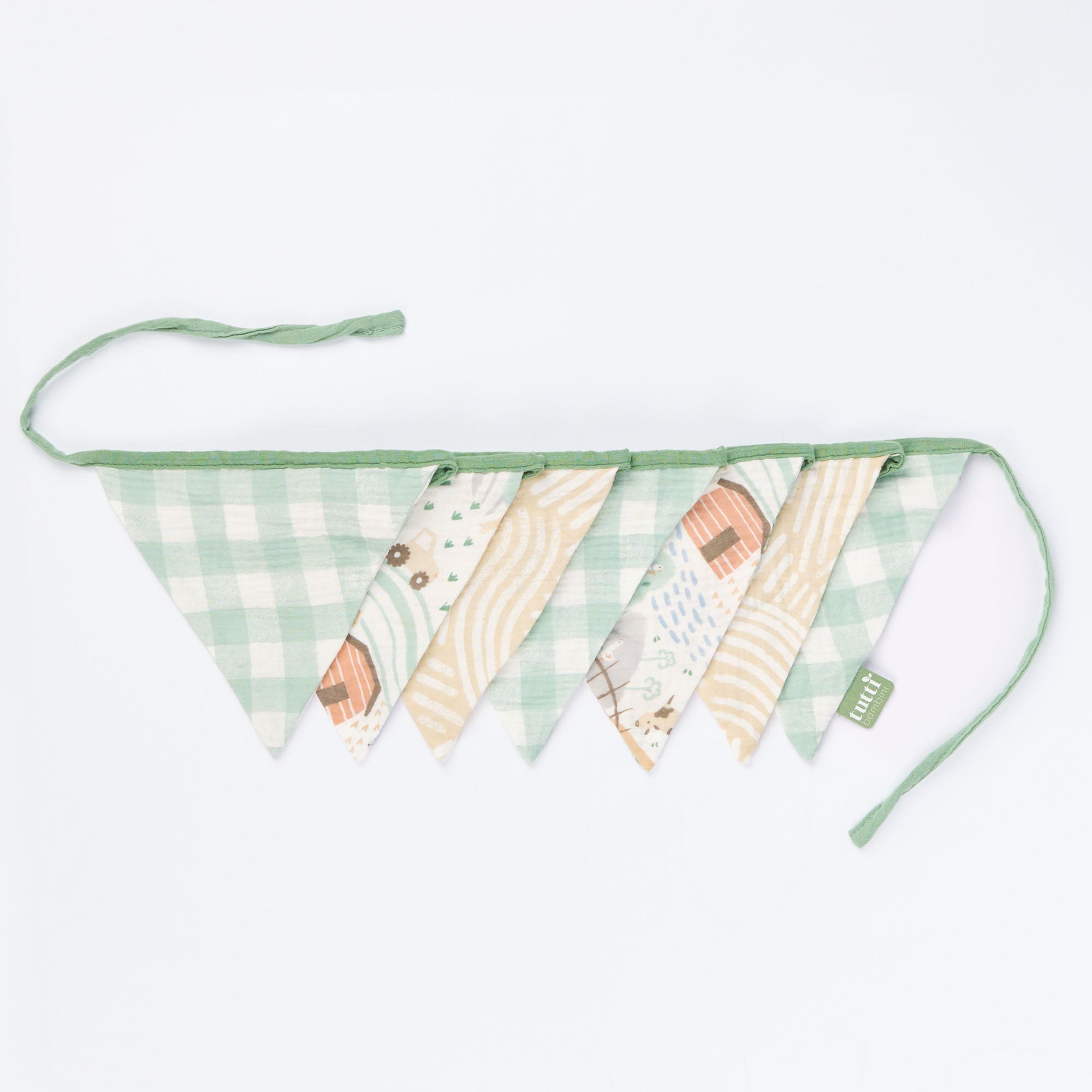 Woodland muslin nursery bunting with gingham and nature prints laid flat, featuring soft green trim and tie ends.