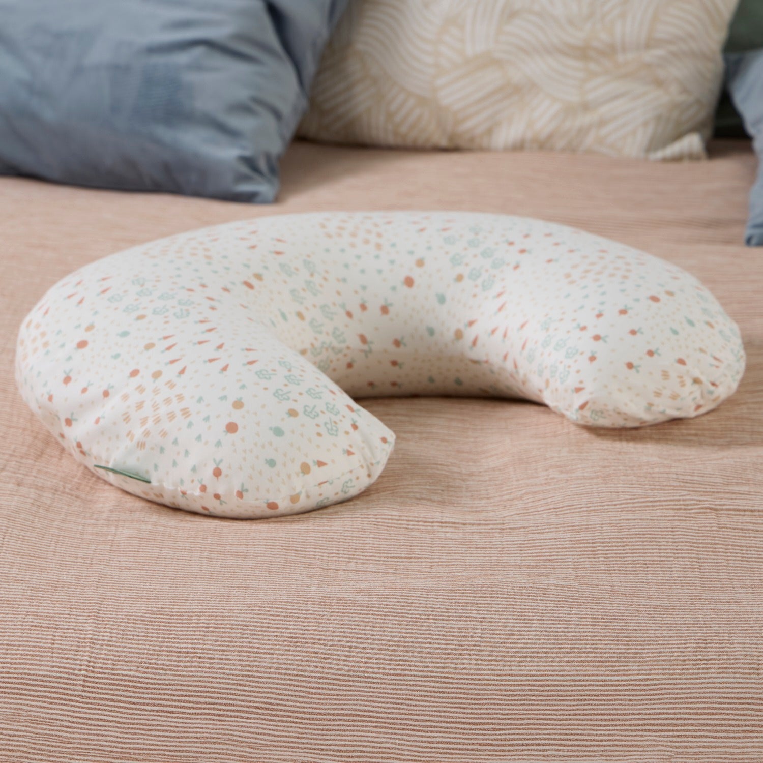 U-shaped feeding pillow with a farm pattern on a bed