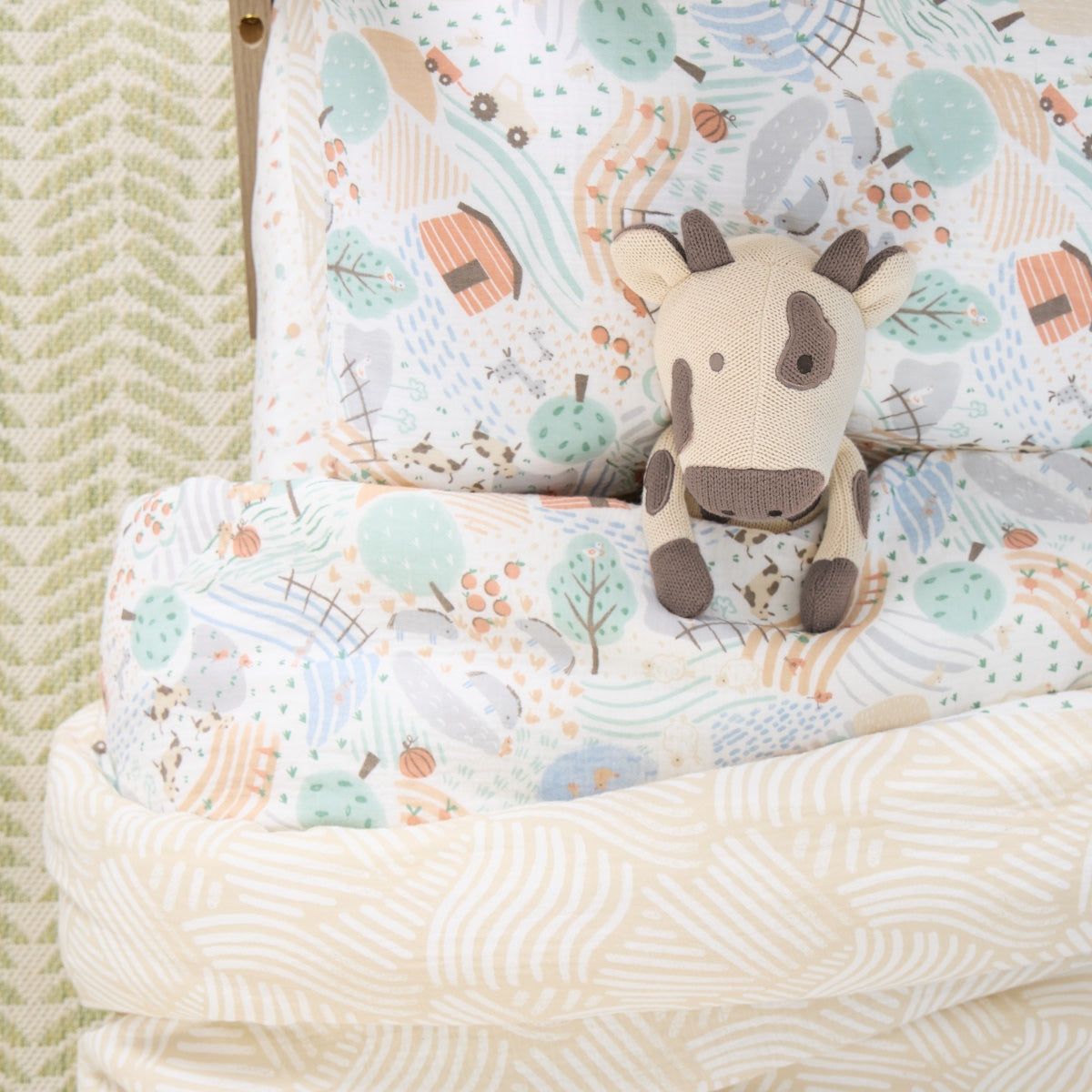 Plush cow toy on a patterned bedding in a bed