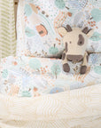 Plush cow toy on a patterned bedding in a bed