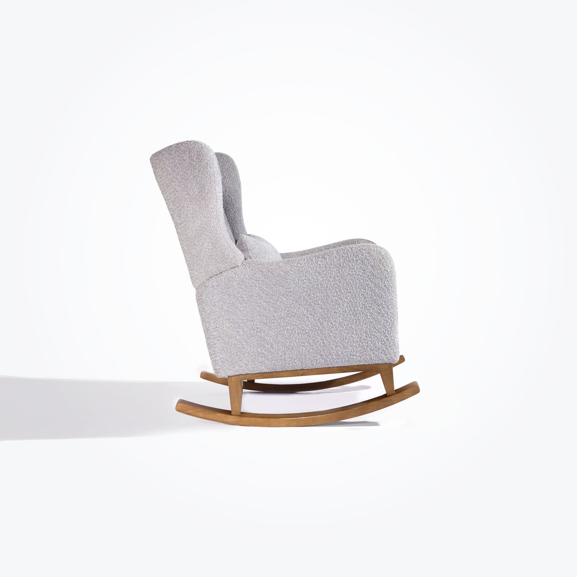 Side cutout of the Harper Wingback rocking chair in boucle cloud grey with oak rockers, showing curved armrests and winged back.