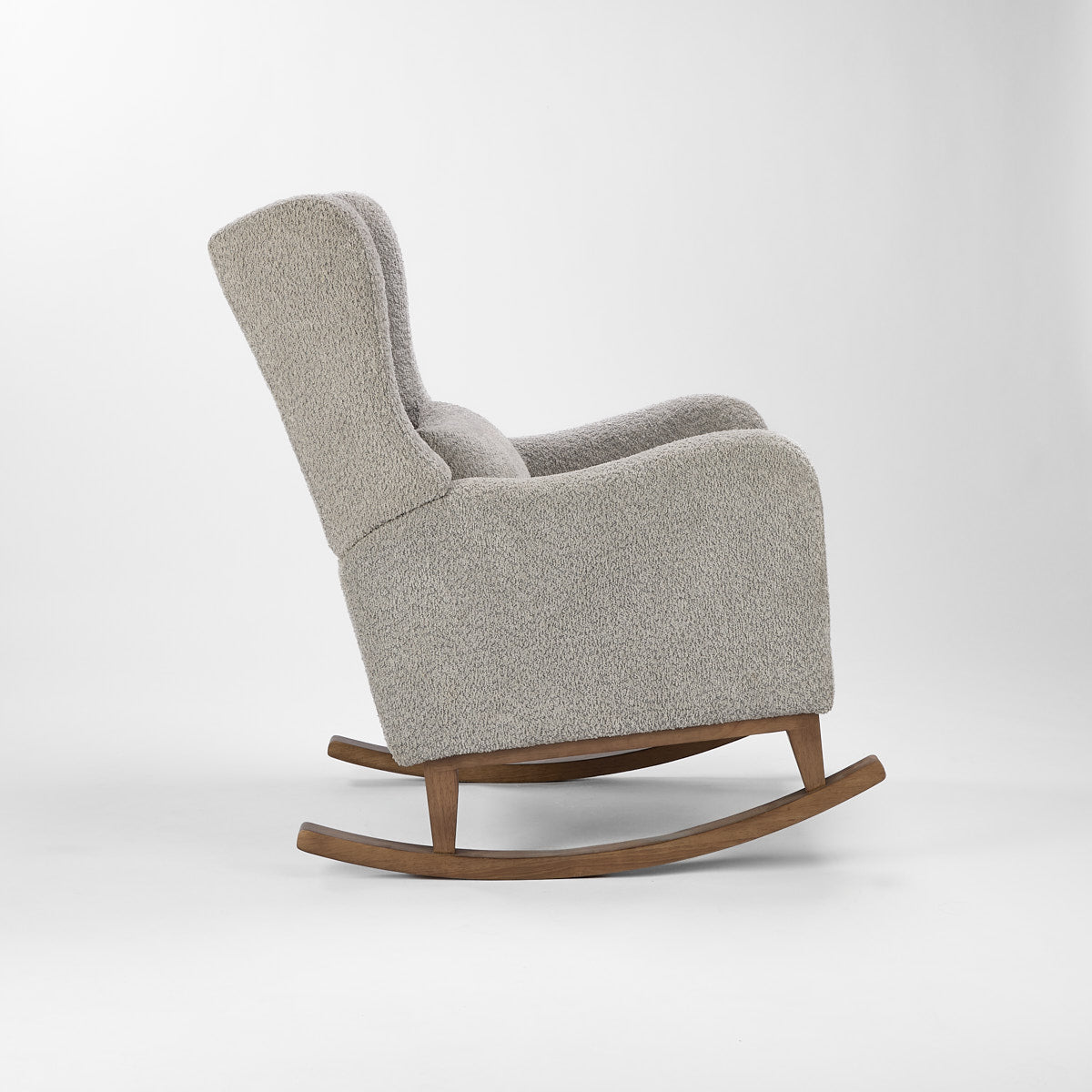 Side cutout of the Harper Wingback rocking chair in boucle cloud grey with oak rockers, showing curved armrests and winged back.