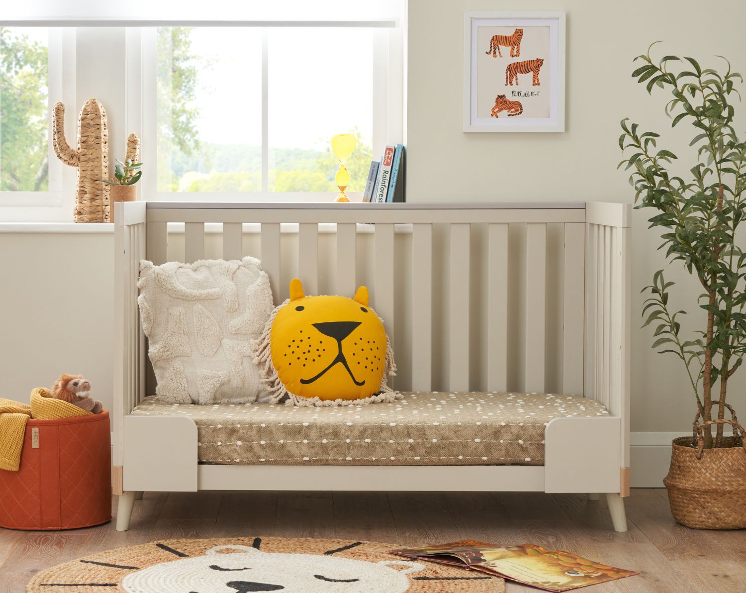 Lifestyle image showing the sofa/day bed mode of the Hygge cot bed in Light Oak/White Sand in a nursery room with Safari decor.