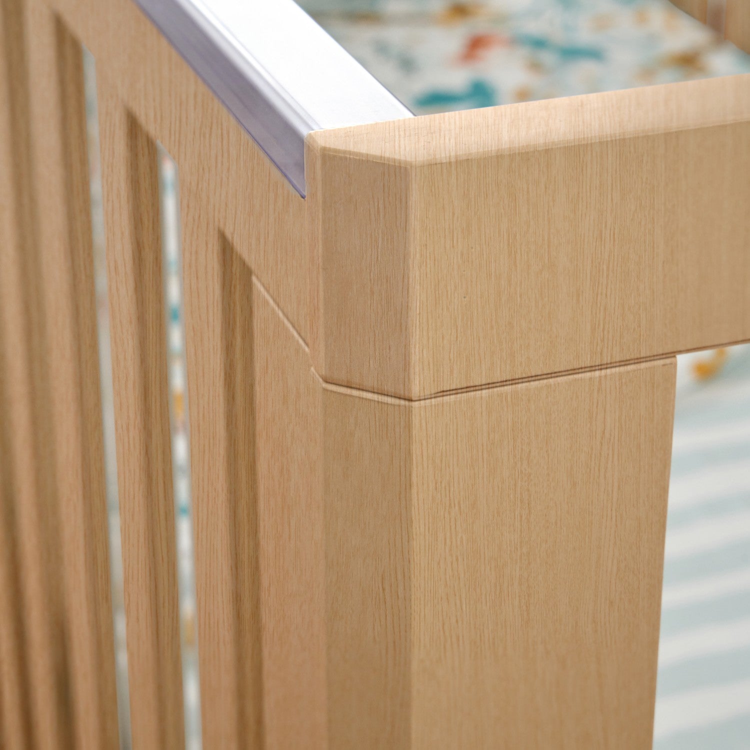 Close-up image of the corner and teething rails of the Hygge cot bed in light oak.