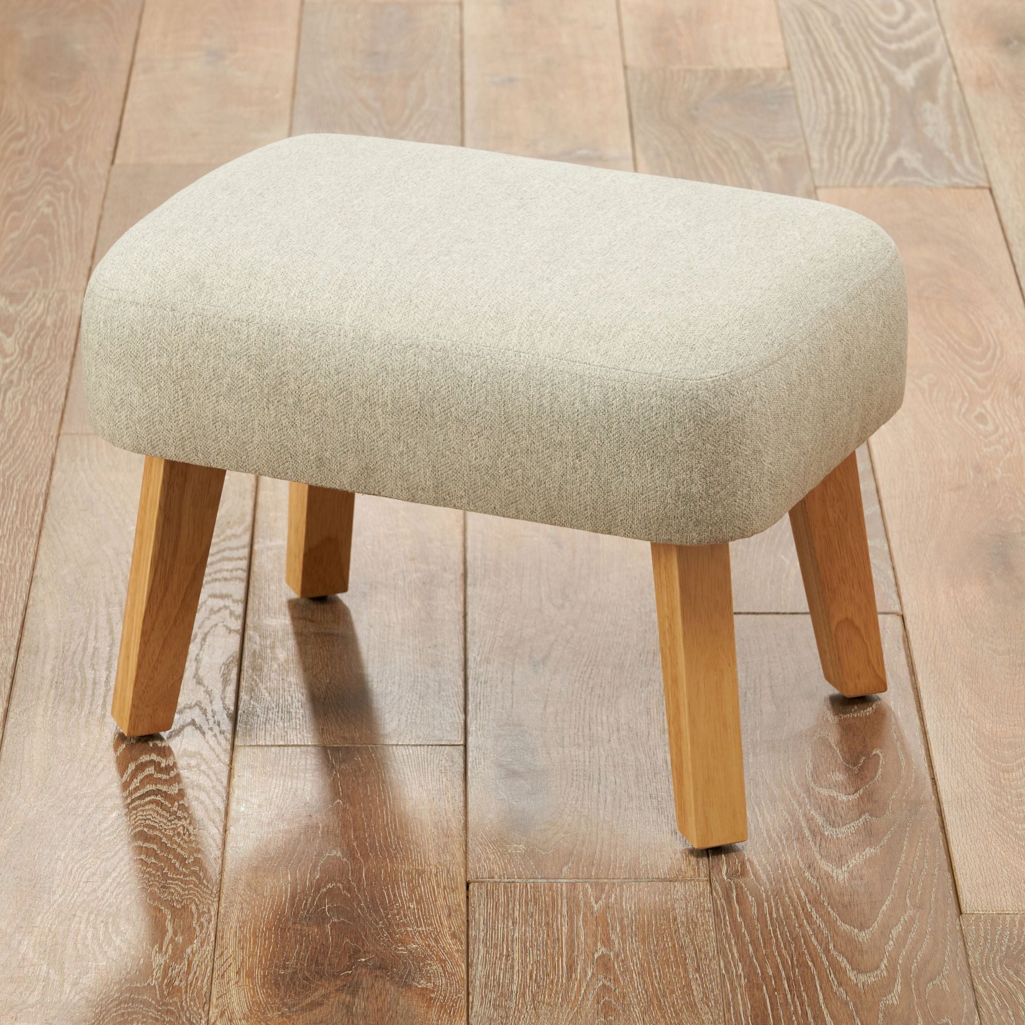 Footstool of the Jonah rocking chair placed on a wooden floor, showing the matching design and finish.