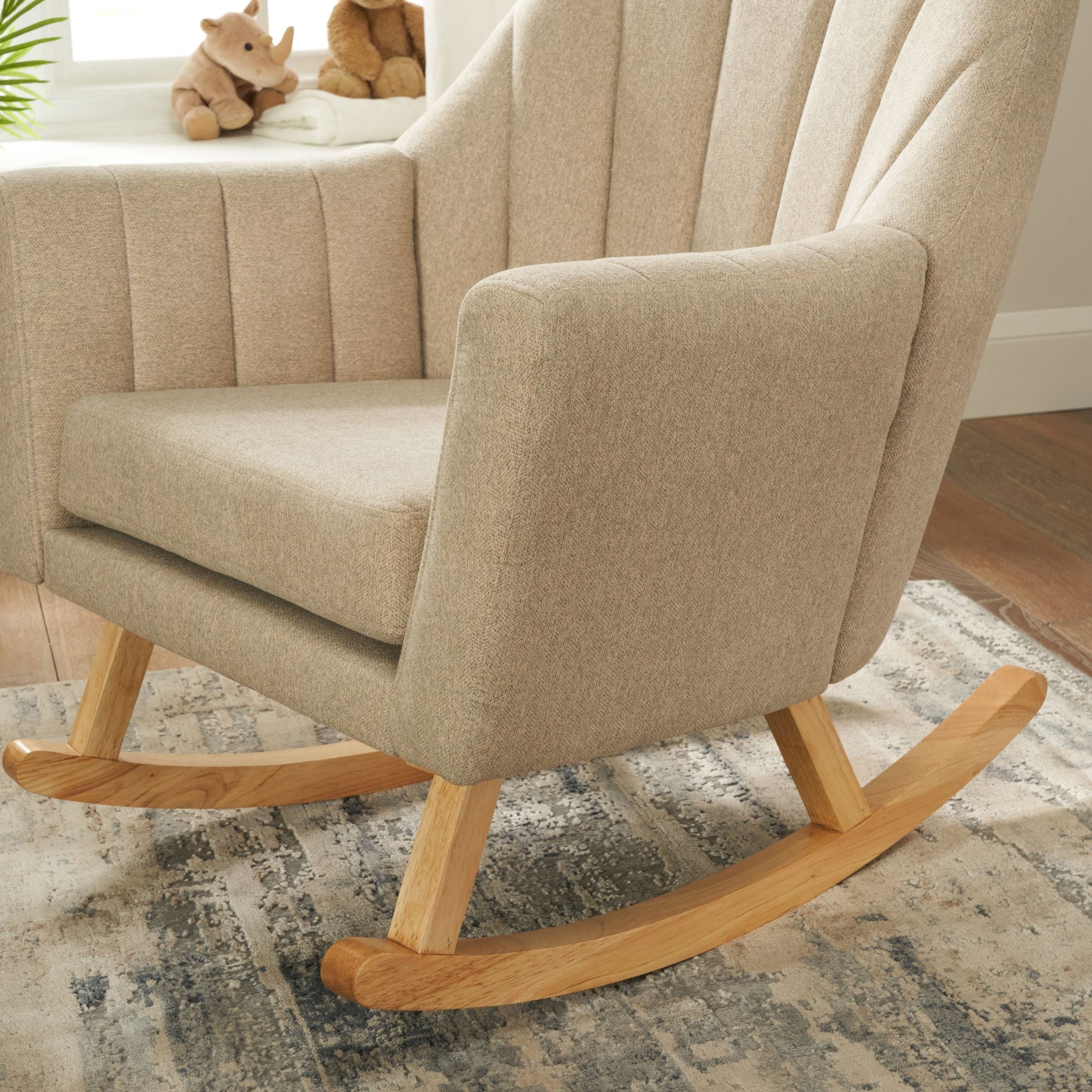 Close-up of the Jonah chair showing the cushioned back and wooden legs, placed on a beige and blue rug