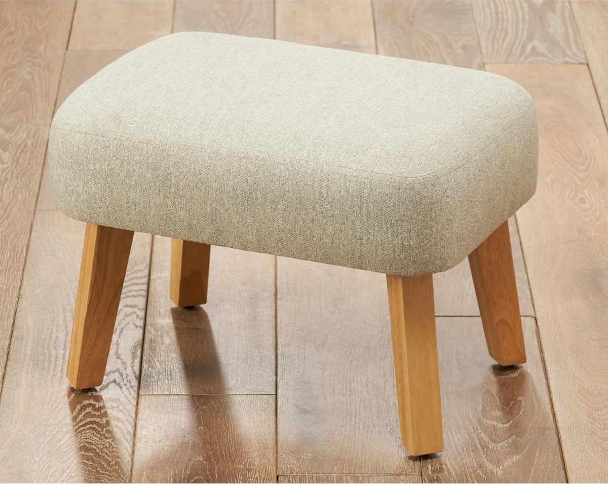 Beige footstool with wooden legs on a wooden floor
