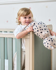 A child playing with her teddy on the Kuba cot bed in sage.