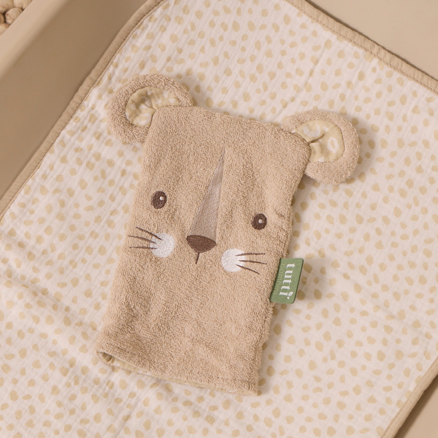 Cat-shaped wash mitt with a tag on a polka dot surface