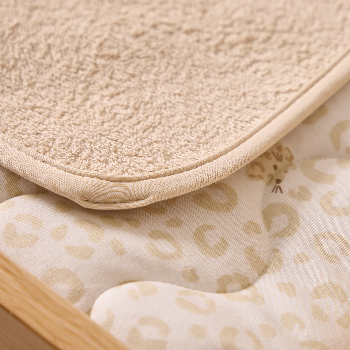 Close-up of a textured beige mat and a patterned fabric with a wooden frame.