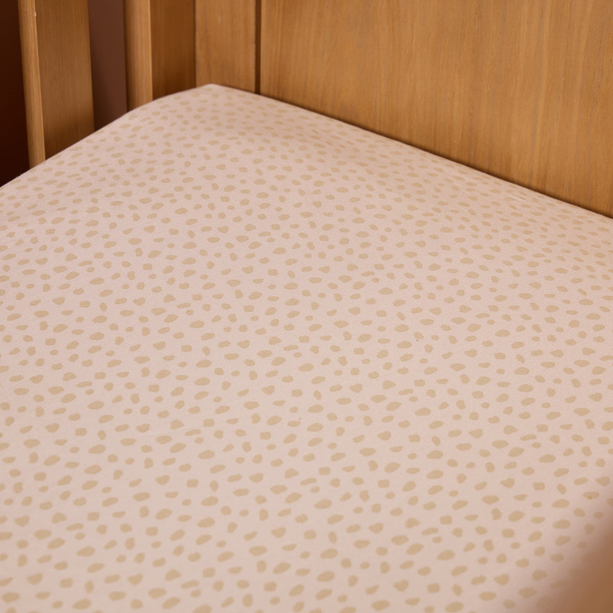 Neutral speckled love cats cot bed fitted sheet styled on wooden cot mattress, highlighting snug fit and soft breathable cotton fabric.