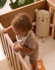 A child is standing in a cot bed with Larry the leopard pillow in the background