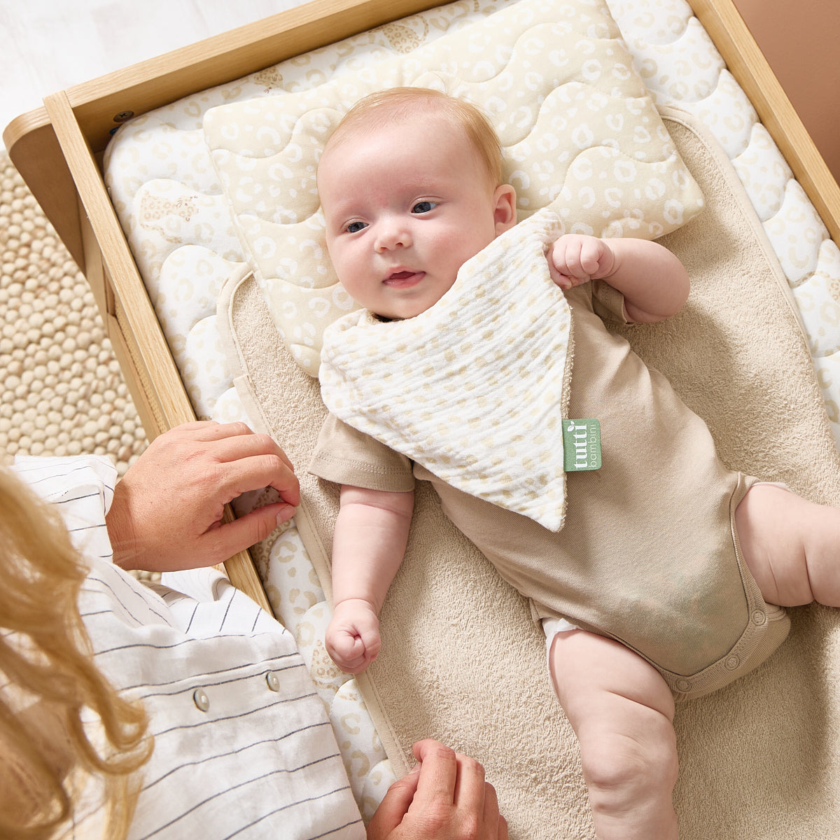 A baby laying on top of the Love Cats luxury changing mat on the Japandi Chest changer.