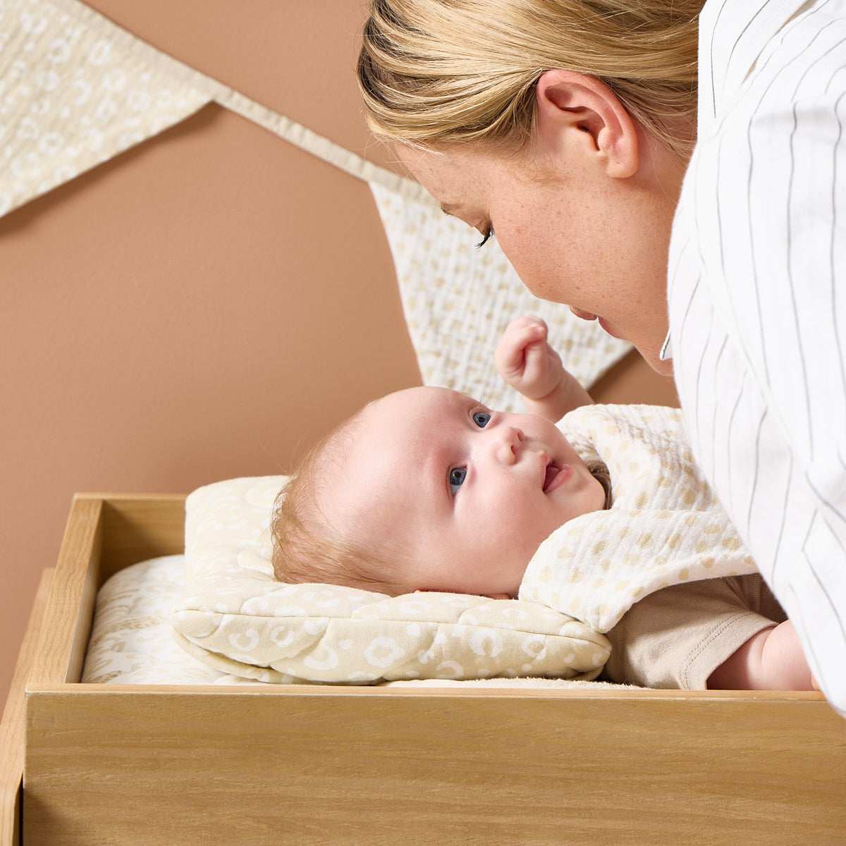 A woman interacting with a baby lying in a wooden chest of drawers with a changing area with the Love Cats luxury changer.