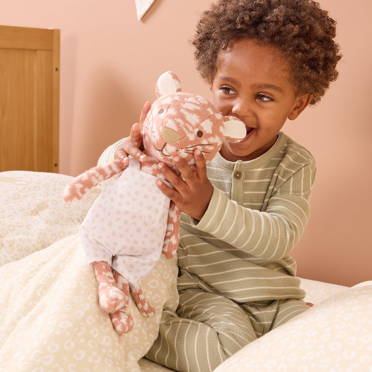 Child holding a tiger plush toy in a cosy room