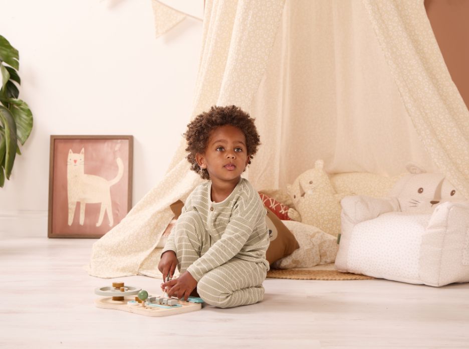 Toddler playing beside a Love Cats canopy and cushions, creating a cosy reading nook with soft neutral tones and cat-themed décor.