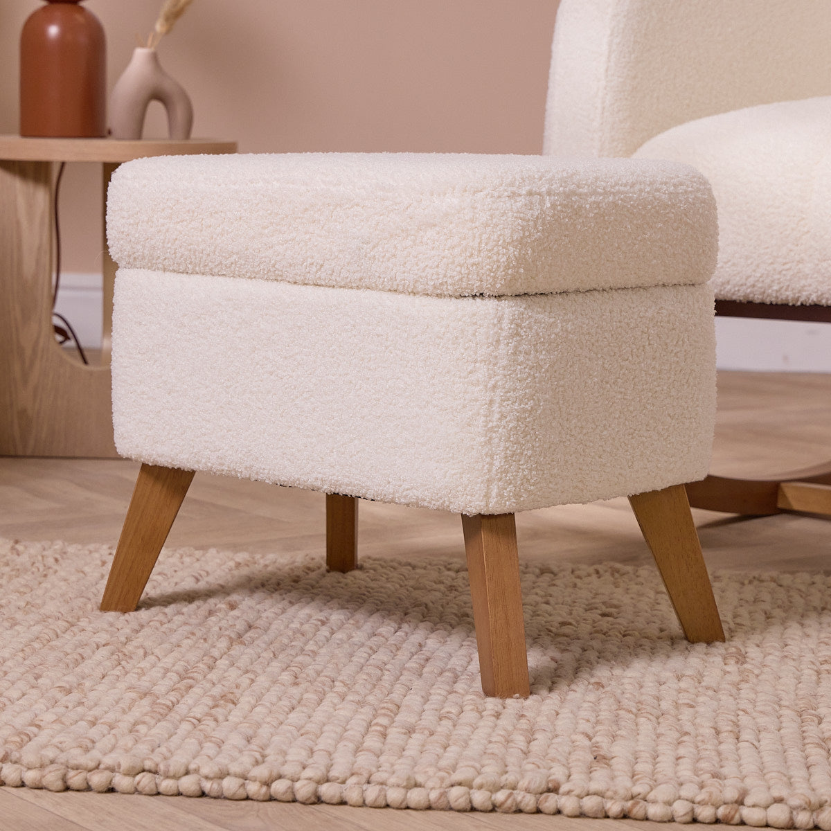 White textured footstool with wooden legs on a beige rug