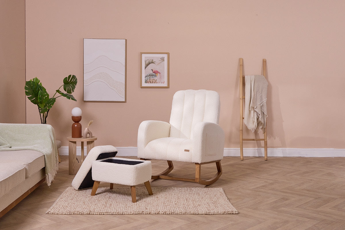 Luca nursing chair in cream with curved lines, low profile, and sculpted wooden legs, in a living room with beige walls and wooden floor.