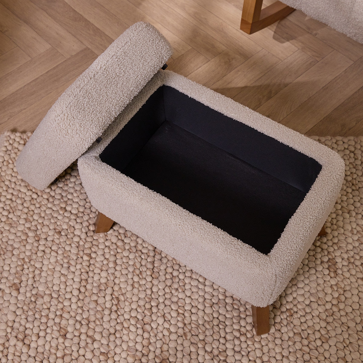 Luca's footstool opened with a plush interior, showcasing its storage capacities, and wooden legs on a carpeted floor.