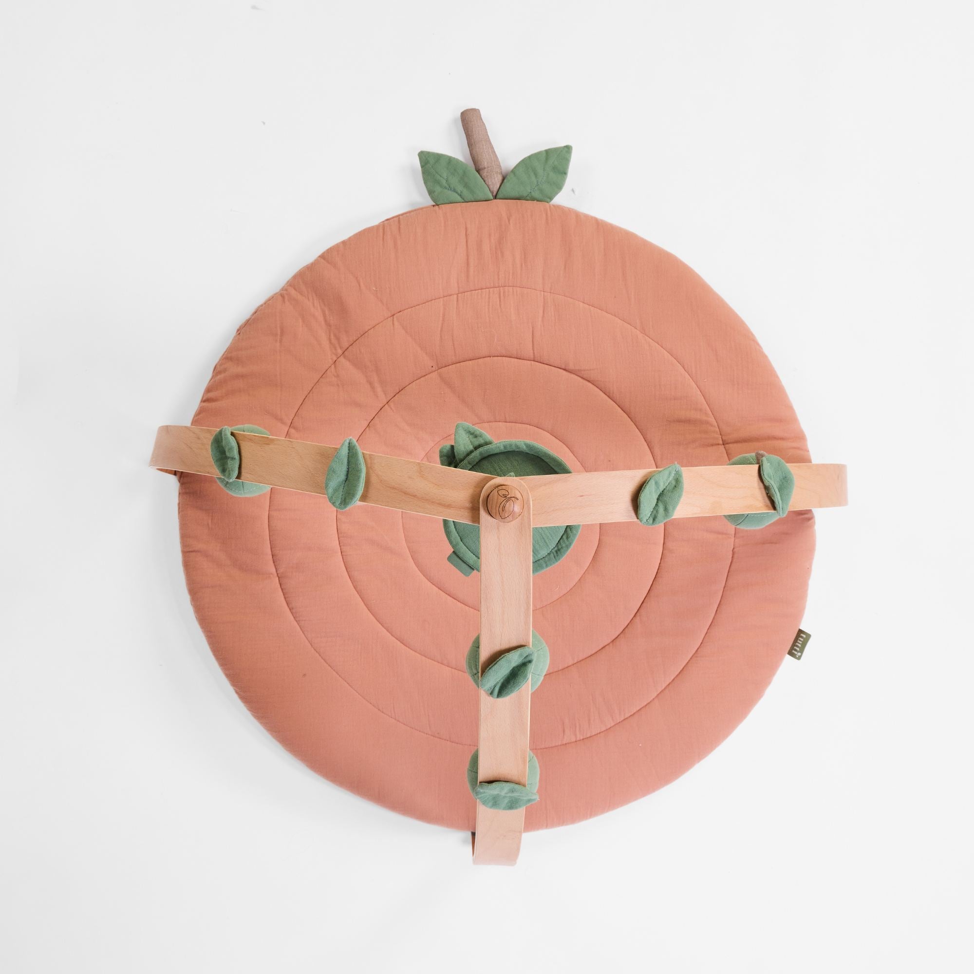 Top-down view of good life terracotta padded playmat with wooden playgym frame and leaf accents.