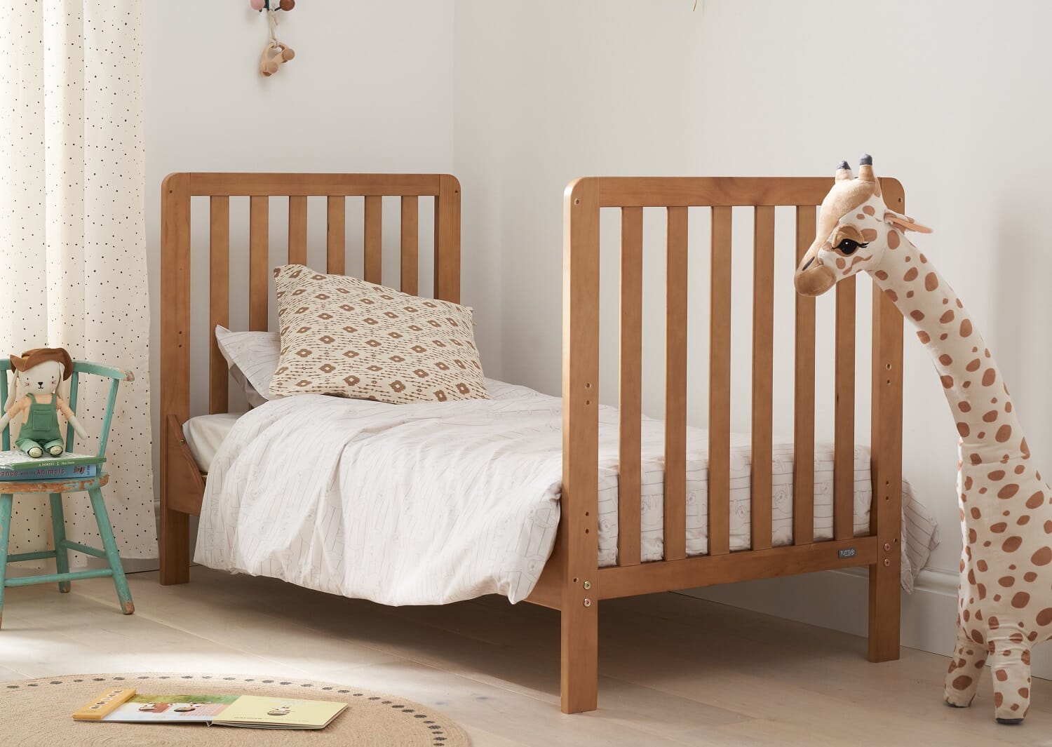 malmo cot bed converted into a toddler bed, showing toy giraffe and tranquille nursery scene.