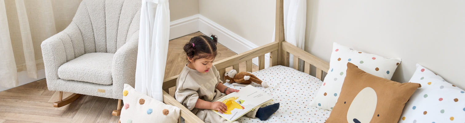 Child reading a book in their casa montessori floor bed