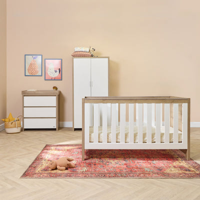 Full nursery view of the Modena white oak cot bed, chest changer and wardrobe, styled together to create a coordinated, modern and calming space