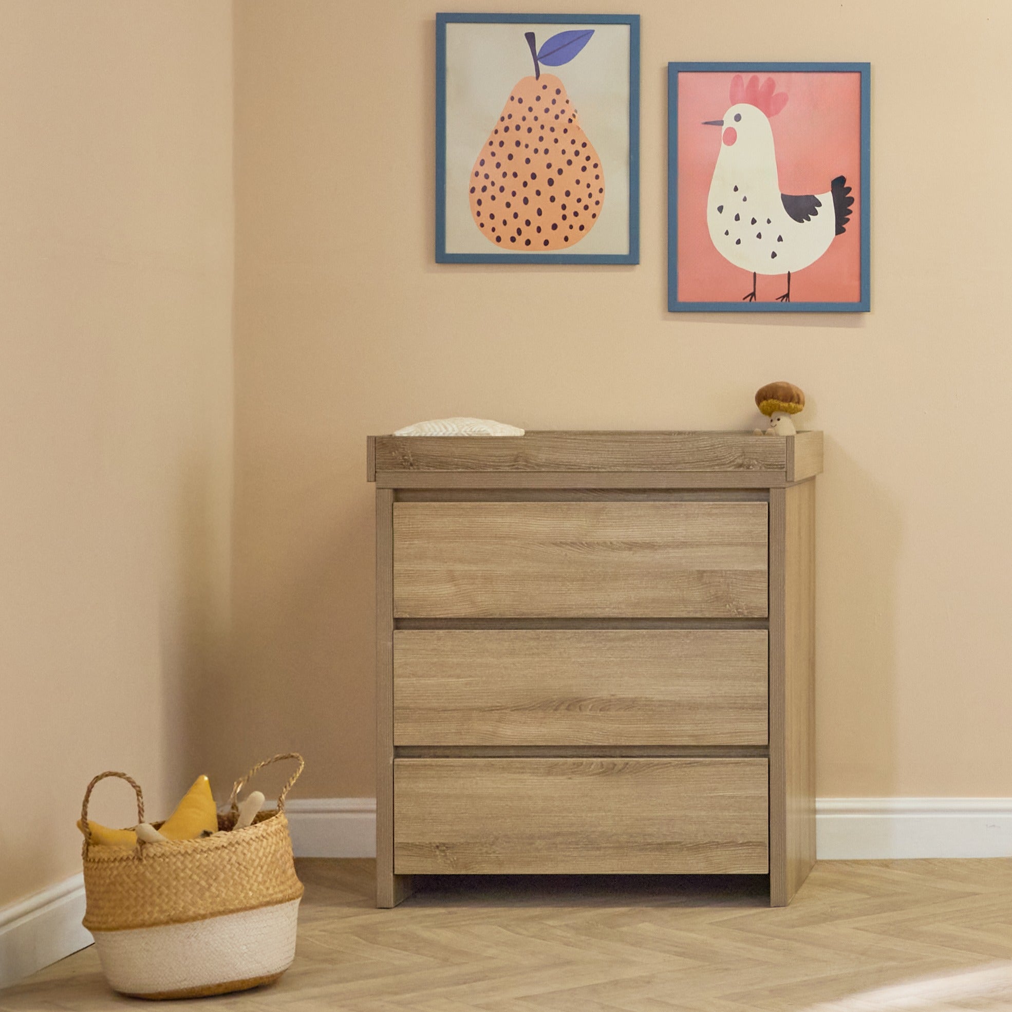 Modena changing unit in oak finish styled in a cosy nursery corner, featuring three roomy drawers and a practical raised changing top