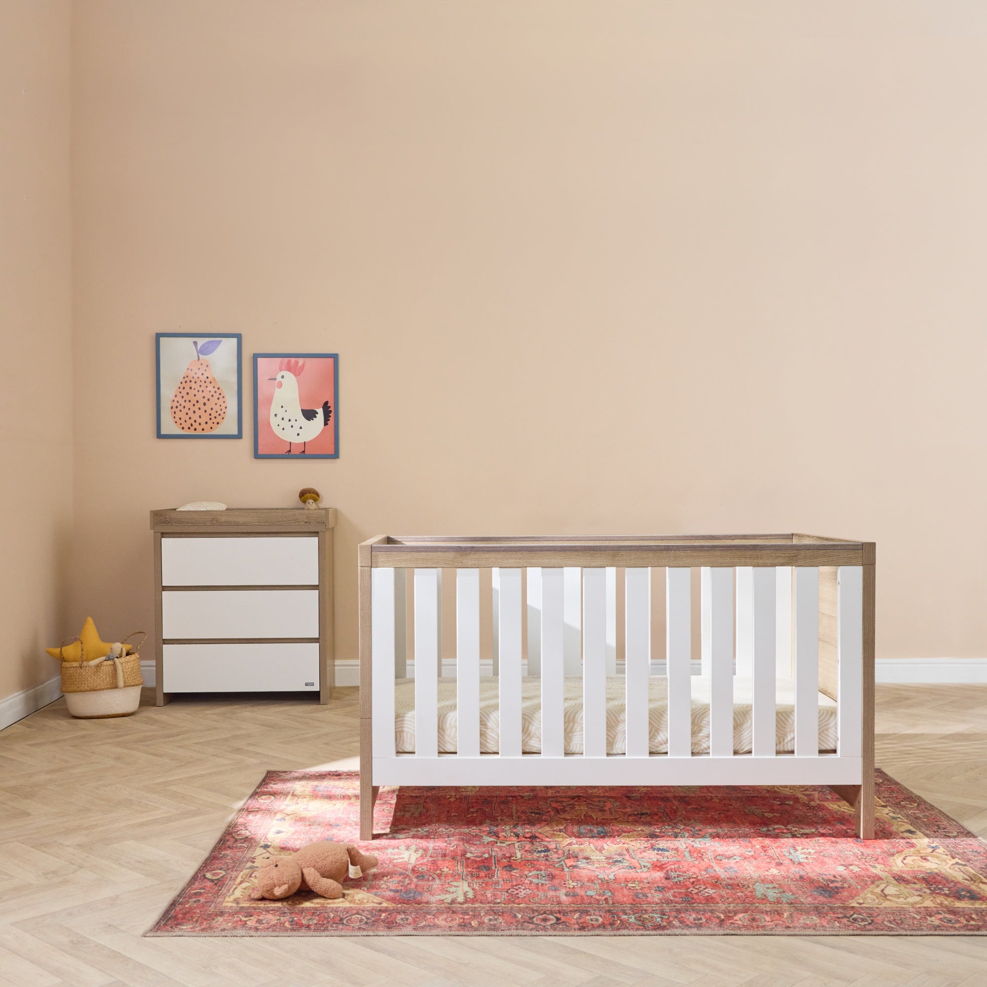 Modena cot bed and matching changing unit in white oak styled in a calm nursery, featuring clean lines, warm wood tones, and a spacious layout