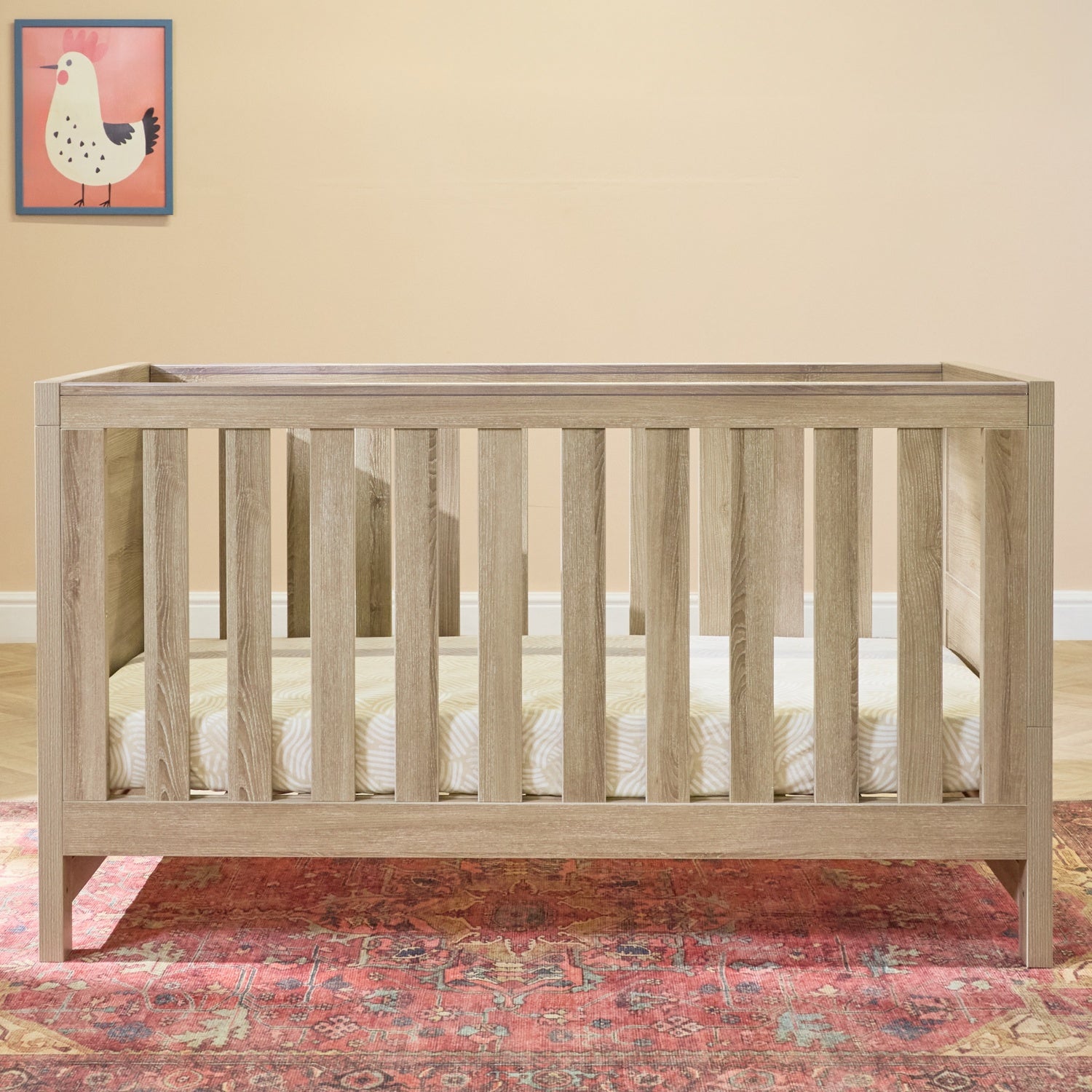 Modena cot bed in oak finish displayed in a calm nursery setting, showing its sturdy slatted sides and spacious sleeping area