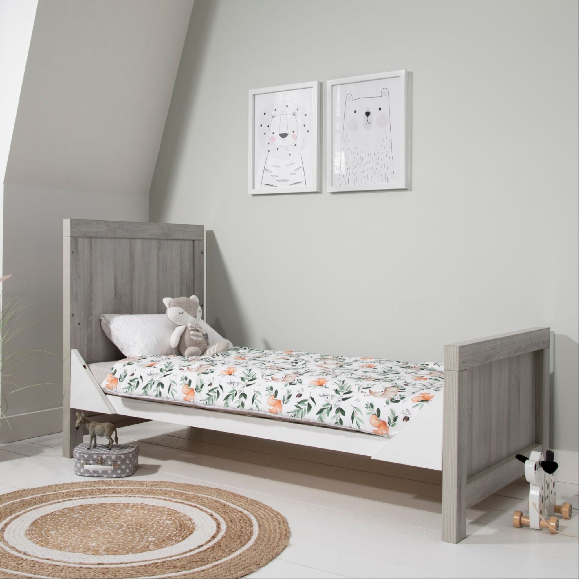 Modena Cot Bed in Grey Ash and White shown in toddler bed mode with woodland-themed bedding, highlighting its adaptability for growing children.