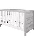 Angled product shot of the Modena Cot Bed in Grey Ash and White with slatted sides and solid panels, perfect for modern nursery interiors.