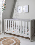 Modena Cot Bed in Grey Ash and White styled in a contemporary nursery, with woodland bedding and decorative accessories, ideal for versatile nursery themes
