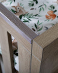 Close-up of the Modena Cot Bed in Oak highlighting the protective teething rail designed to prevent damage from teething babies.