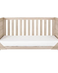 Modena Cot Bed in Oak converted into a versatile sofa bed, offering multi-functional nursery furniture that adapts as your child grows.