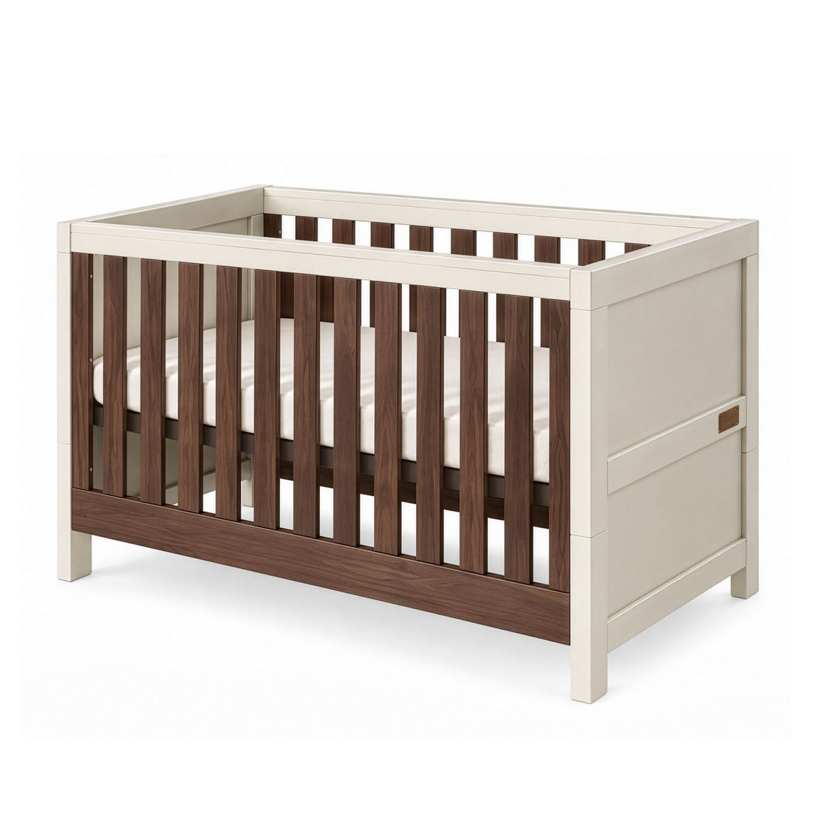 An angle view of the Modena cot bed in cashmere and rich walnut featuring clean lines, slatted sides, and a neutral wood finish for a contemporary nursery.