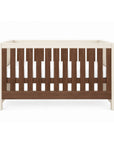 The Modena cot bed in cashmere and rich walnut featuring clean lines, slatted sides, and a neutral wood finish for a contemporary nursery.