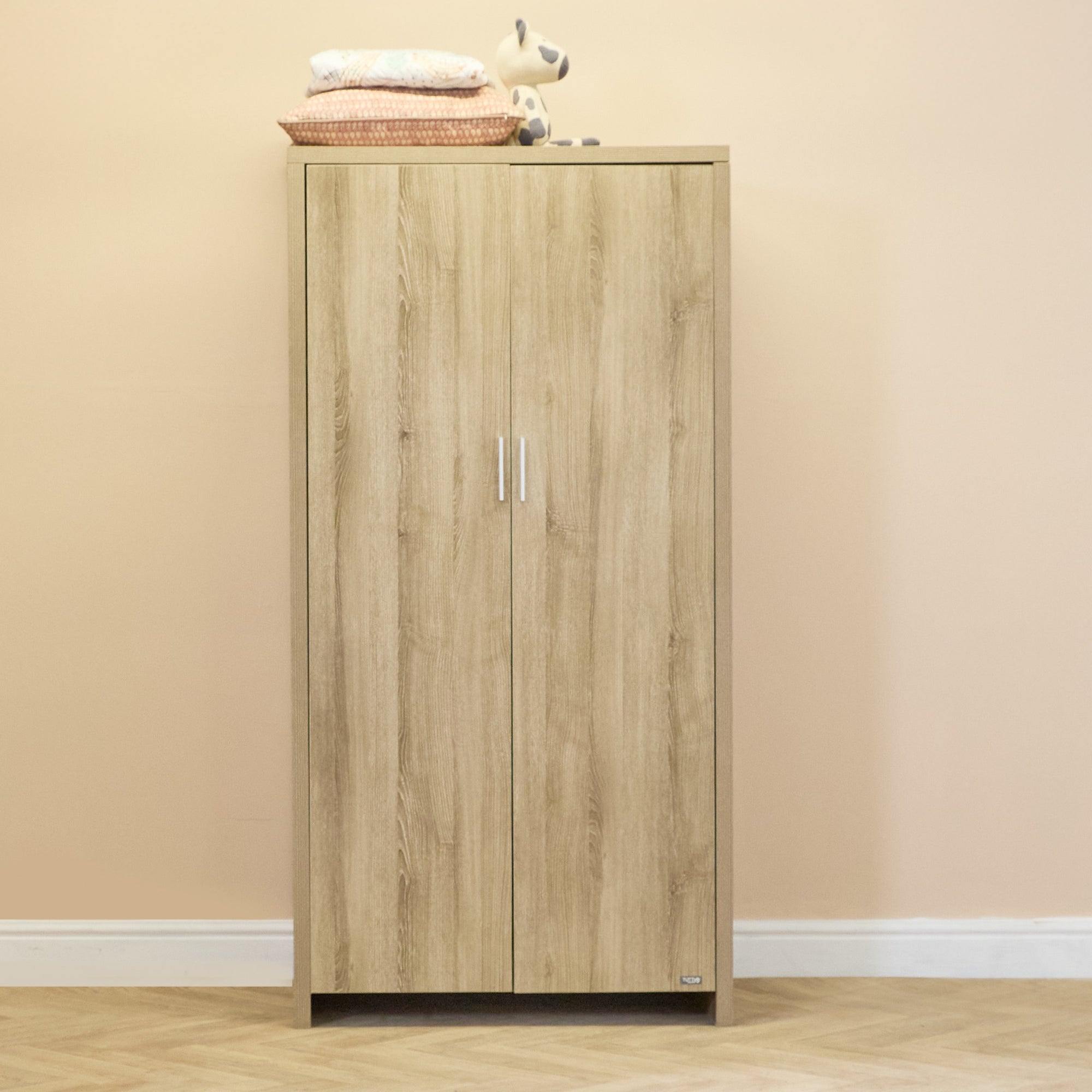Modena wardrobe in oak finish shown in a soft neutral nursery, highlighting full-length doors and generous internal storage