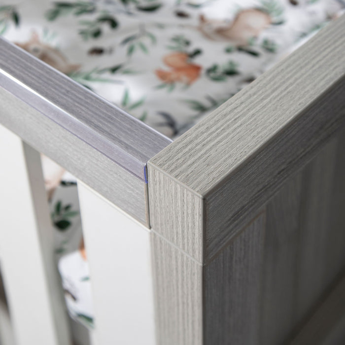 Close-up view of the Modena Cot Bed in Grey and White highlighting protective teething rails and slatted sides, designed for both safety and durability in a modern nursery.