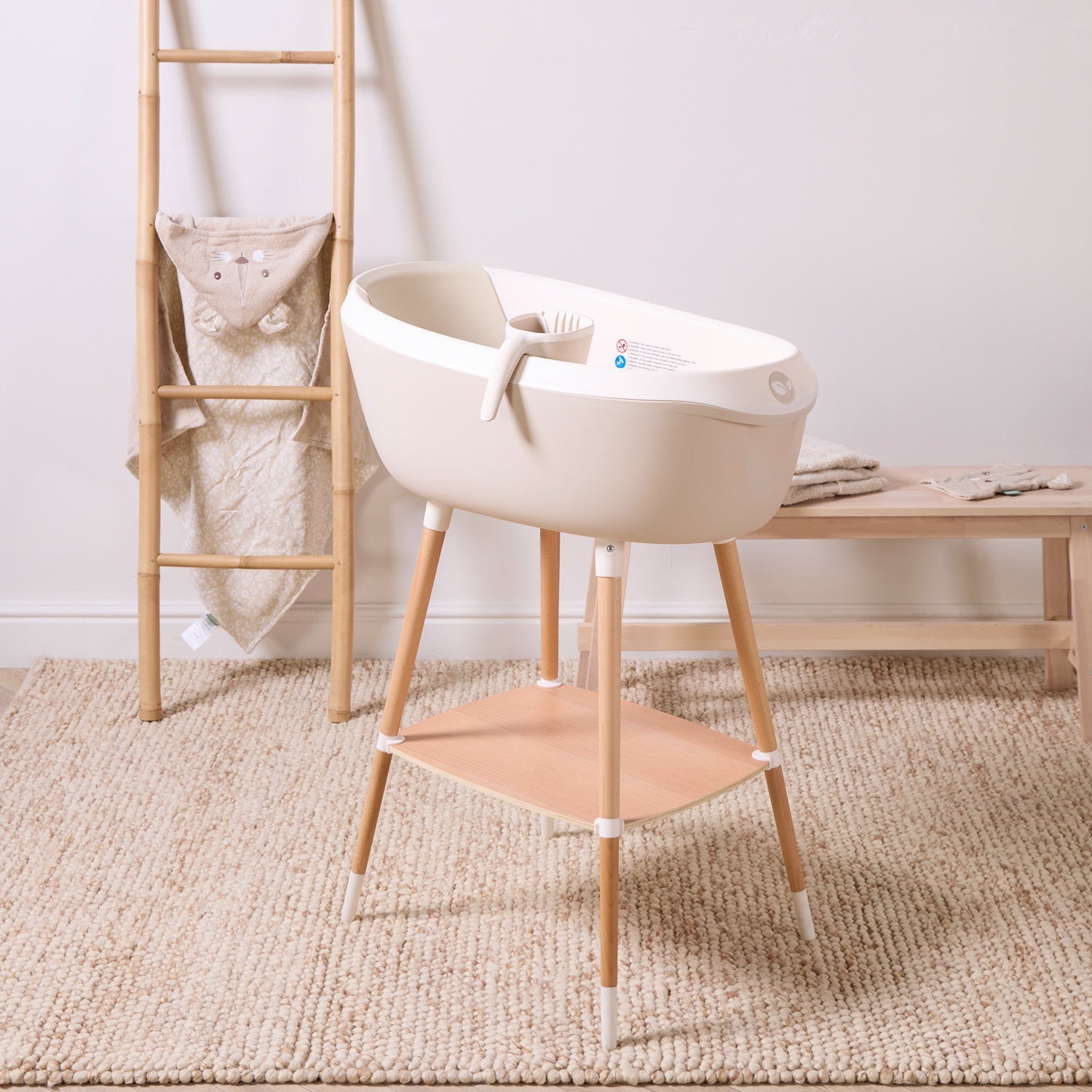 Nati Baby Bath in dune on wooden stand with matching jug and storage shelf for comfortable everyday baby bath time.