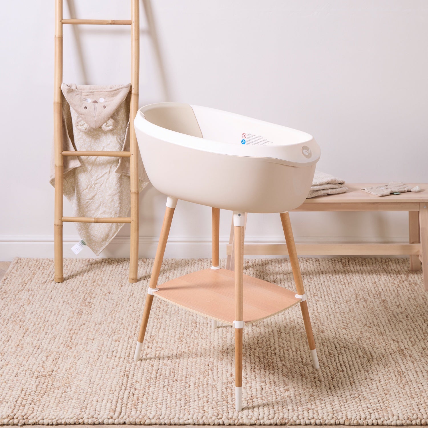 Nati Baby Bath in dune on wooden stand, styled in a soft neutral nursery-inspired bathroom setting.