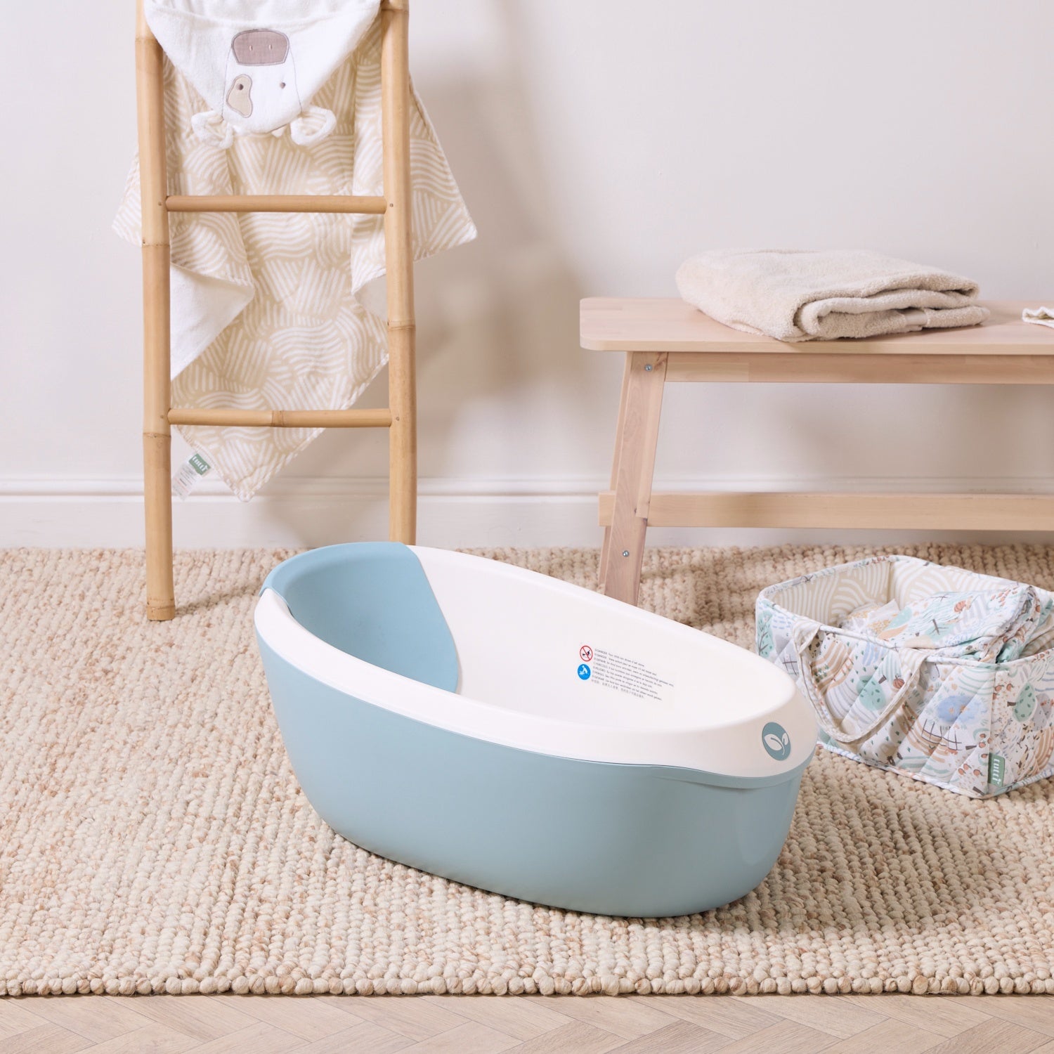 Nati Baby Bath in ocean placed on a textured rug with soft neutral accessories, creating a calm and practical bath space.